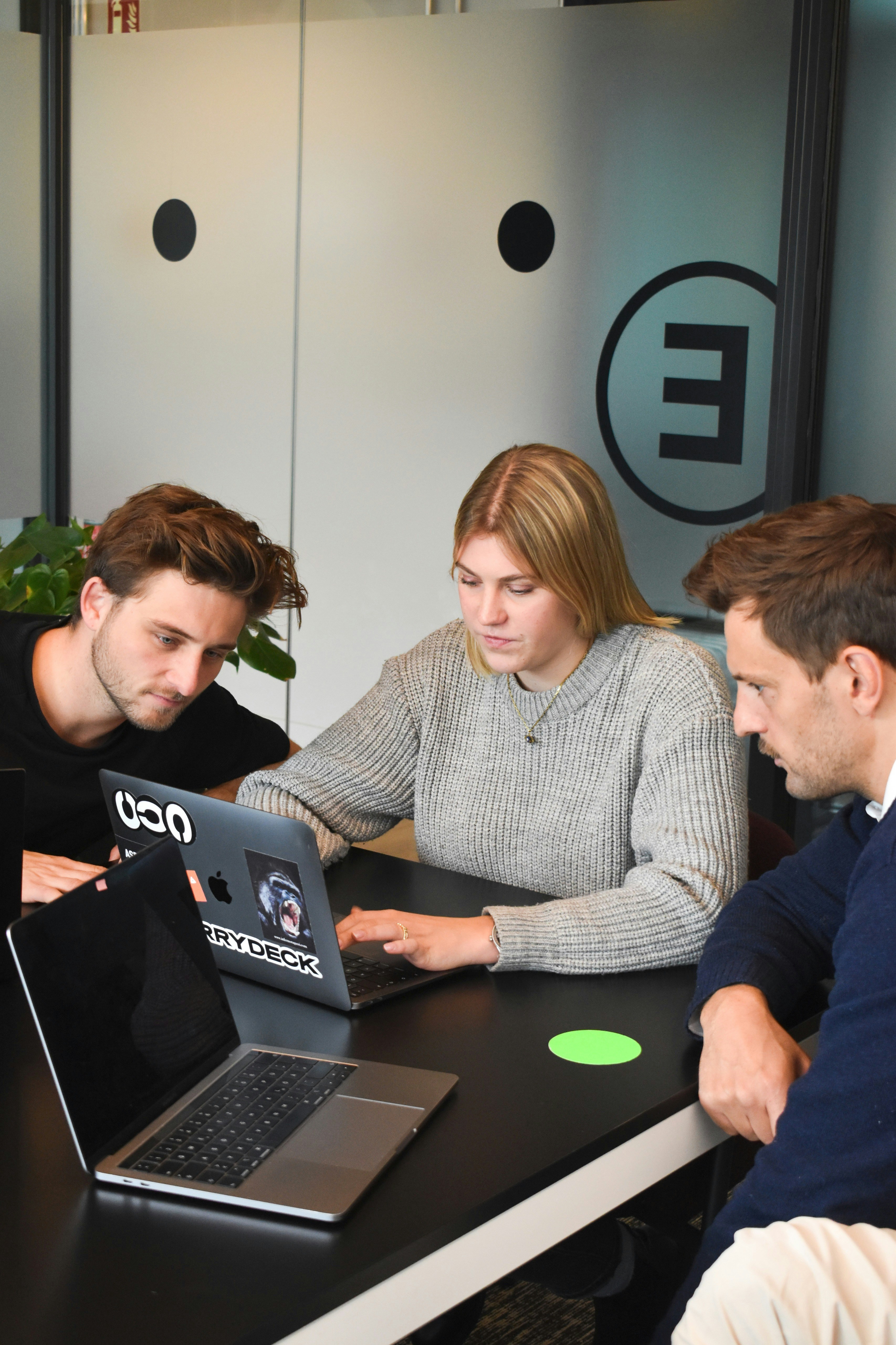 Three colleagues collaborate around a laptop during a software accessibility procurement review.