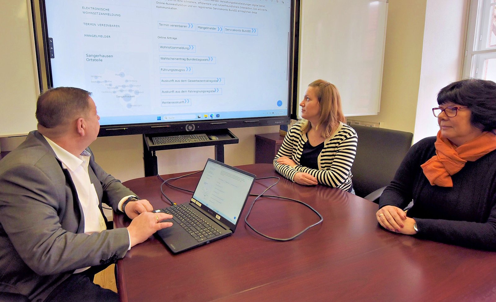 ADA Title II digital government readiness Municipal staff review an online government service on a laptop and large display.