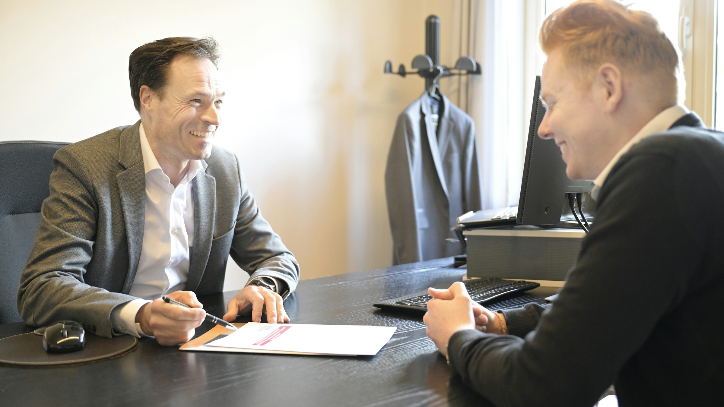 Two professionals review documents together during a business consultation at an office desk.