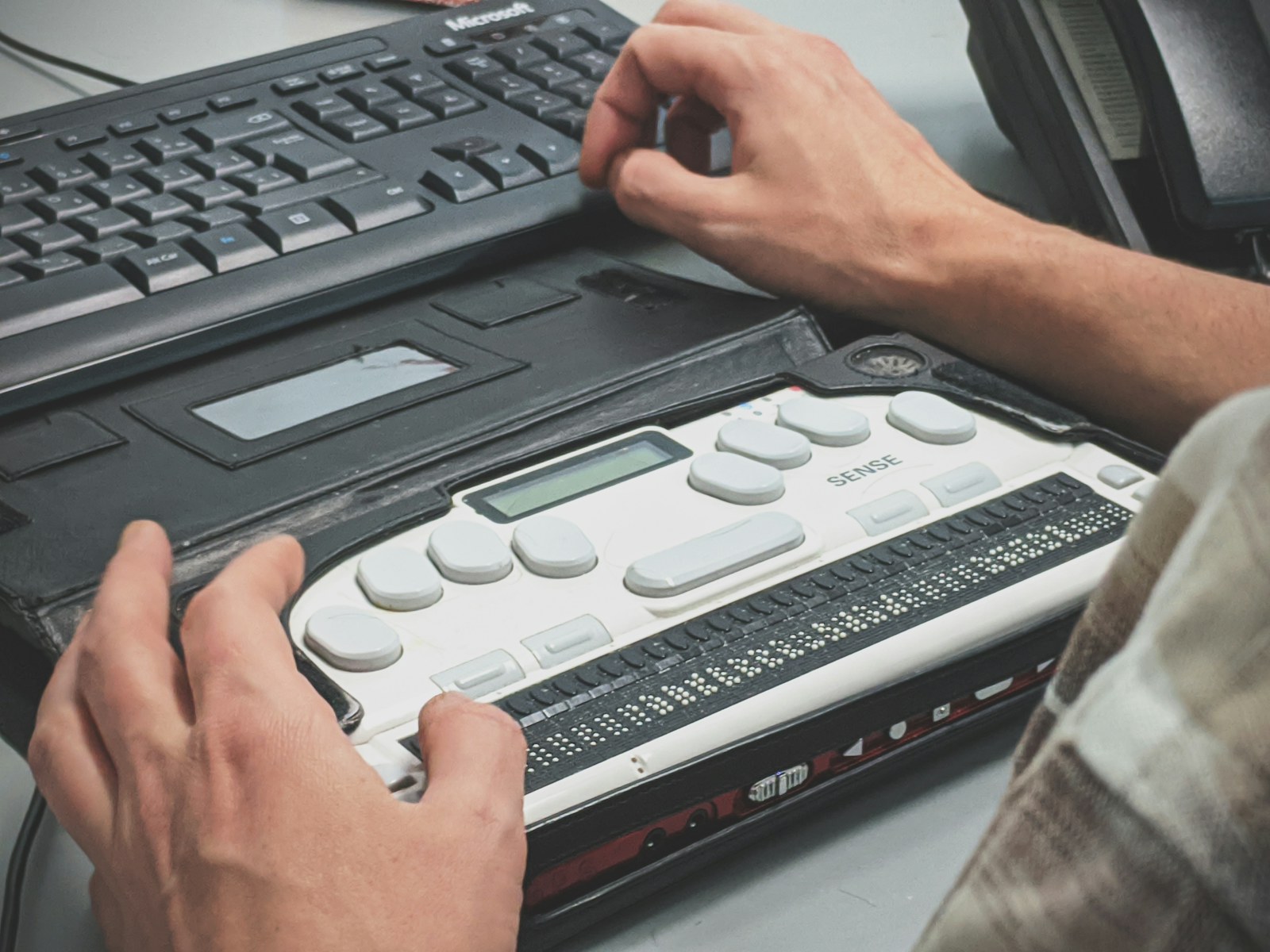 Blind computer user works with a braille display as part of assistive technology testing.