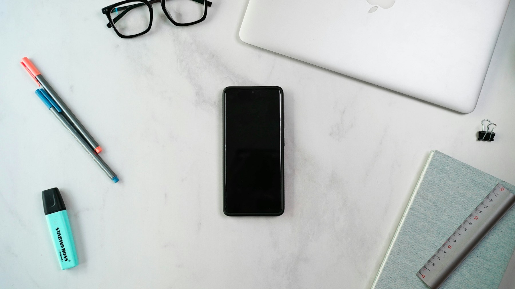 Laptop, notebook, phone, and glasses arranged for a documented website review.