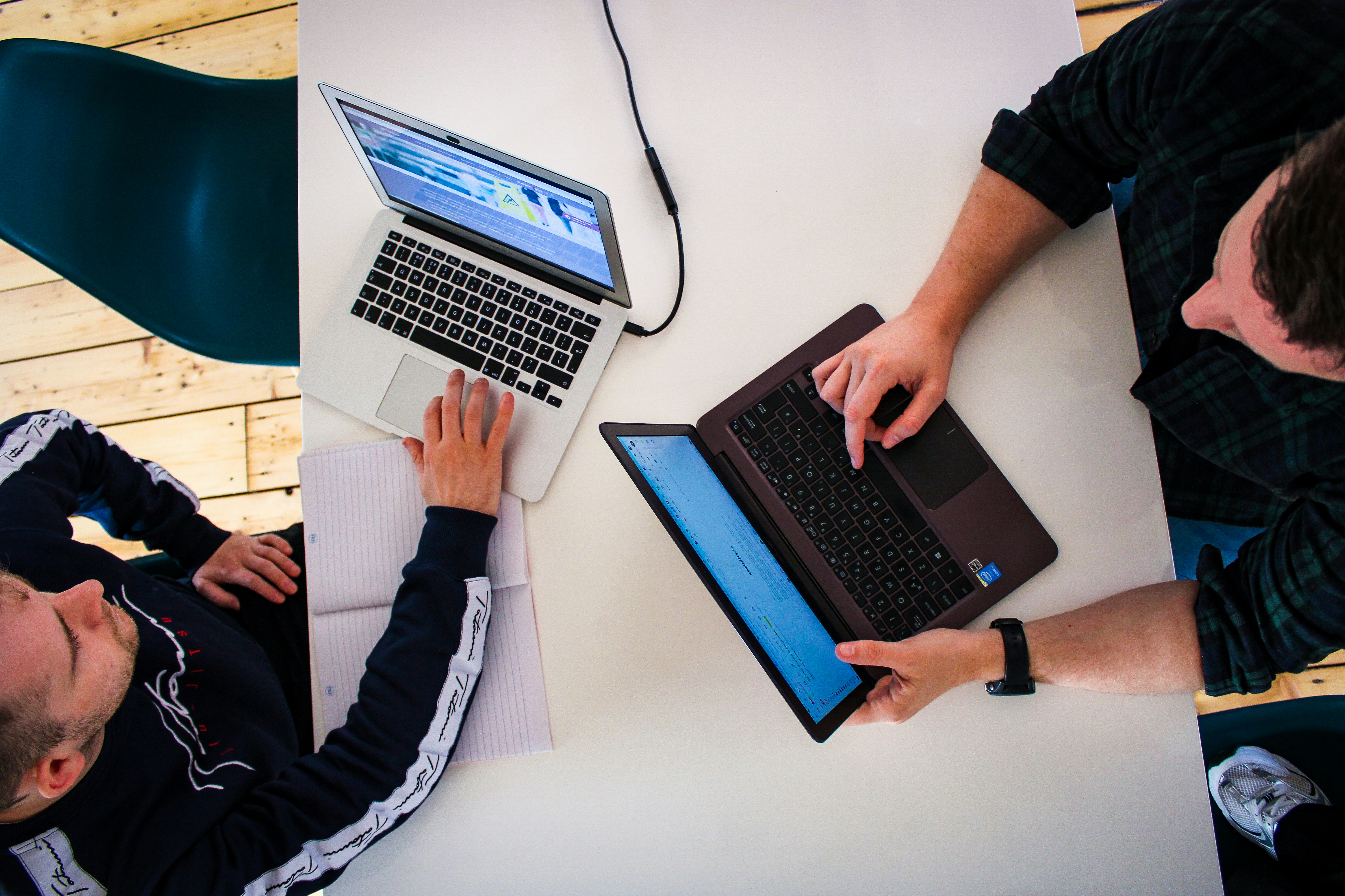Two professionals review website findings on laptops while documenting accessibility testing results.
