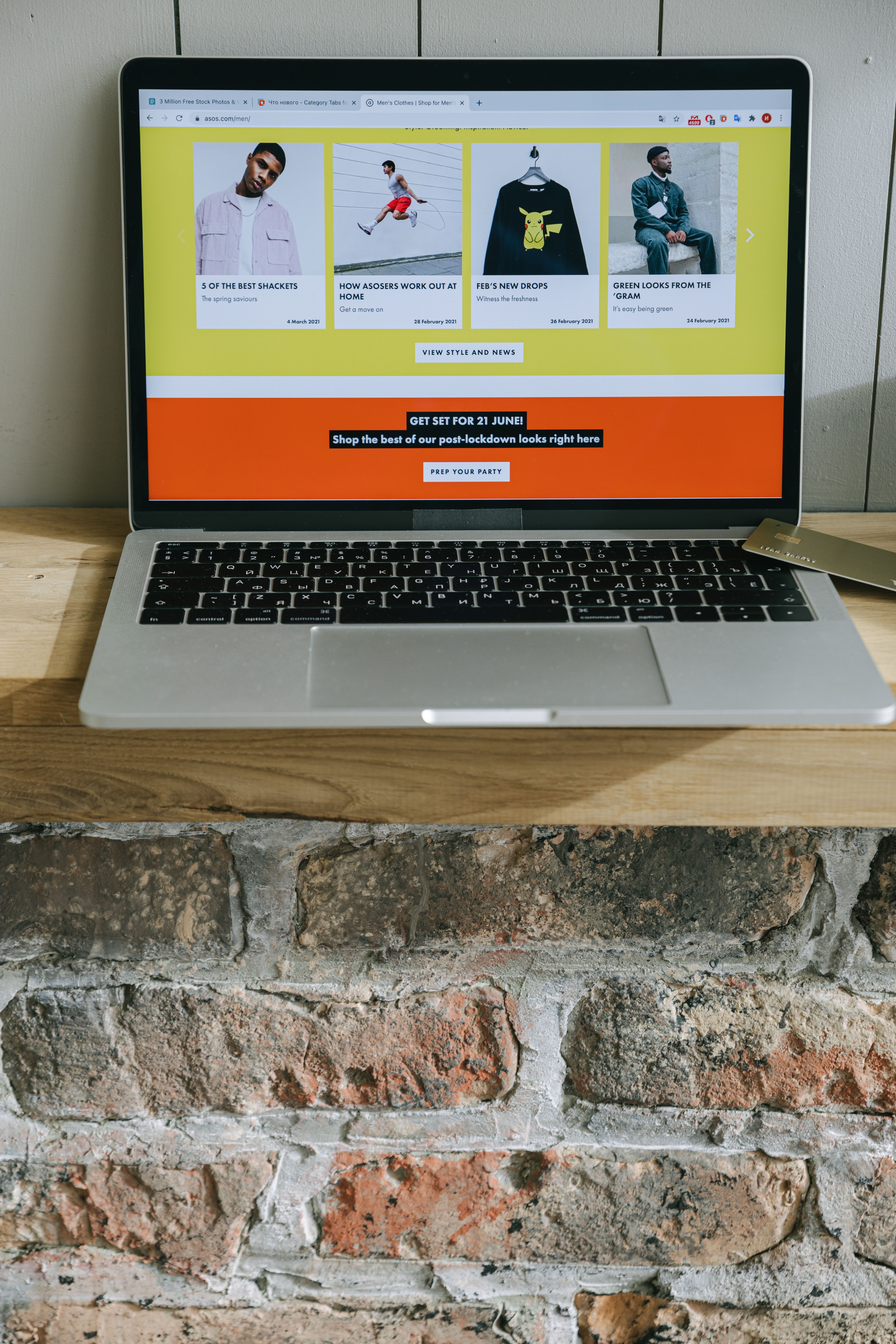 Laptop on a wooden shelf showing a colorful online shopping website with product listings.
